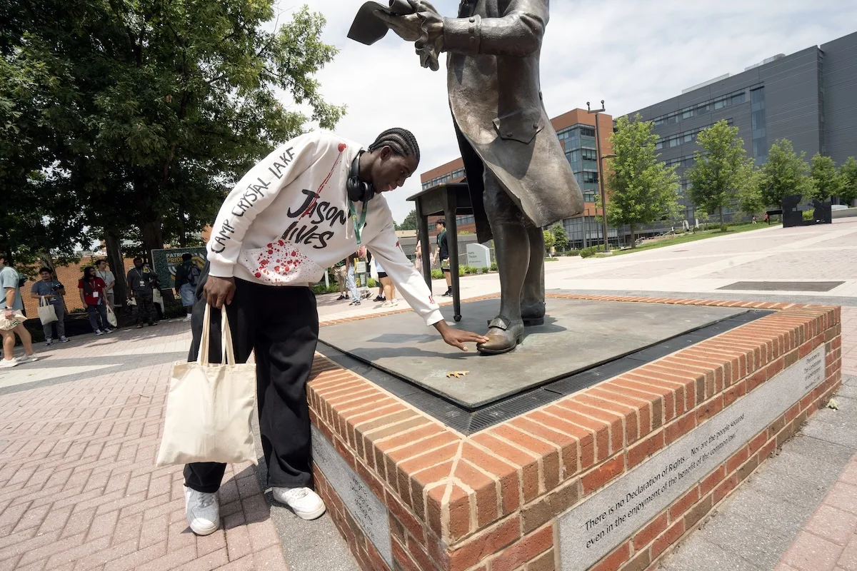An incoming student touches the George Mason statue's left foot.