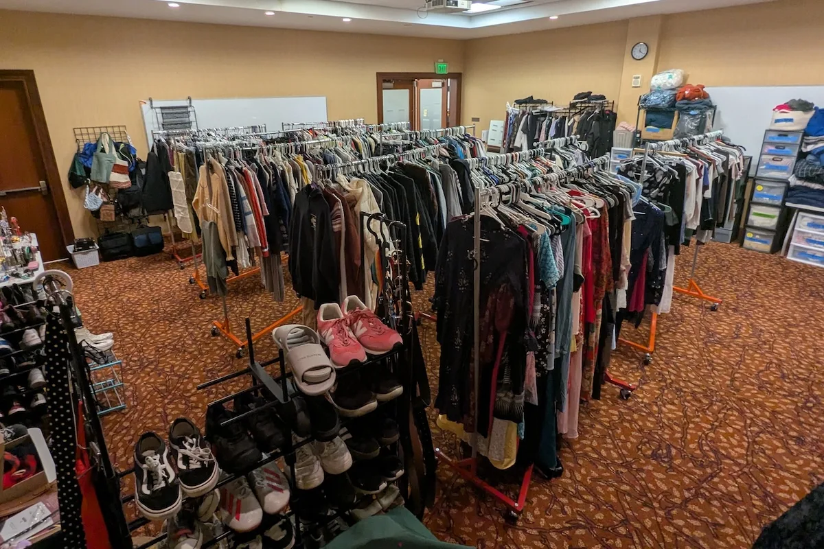 Rows of clothing racks with donated apparel items, from shoes to clothes, pants to purses, and accessories